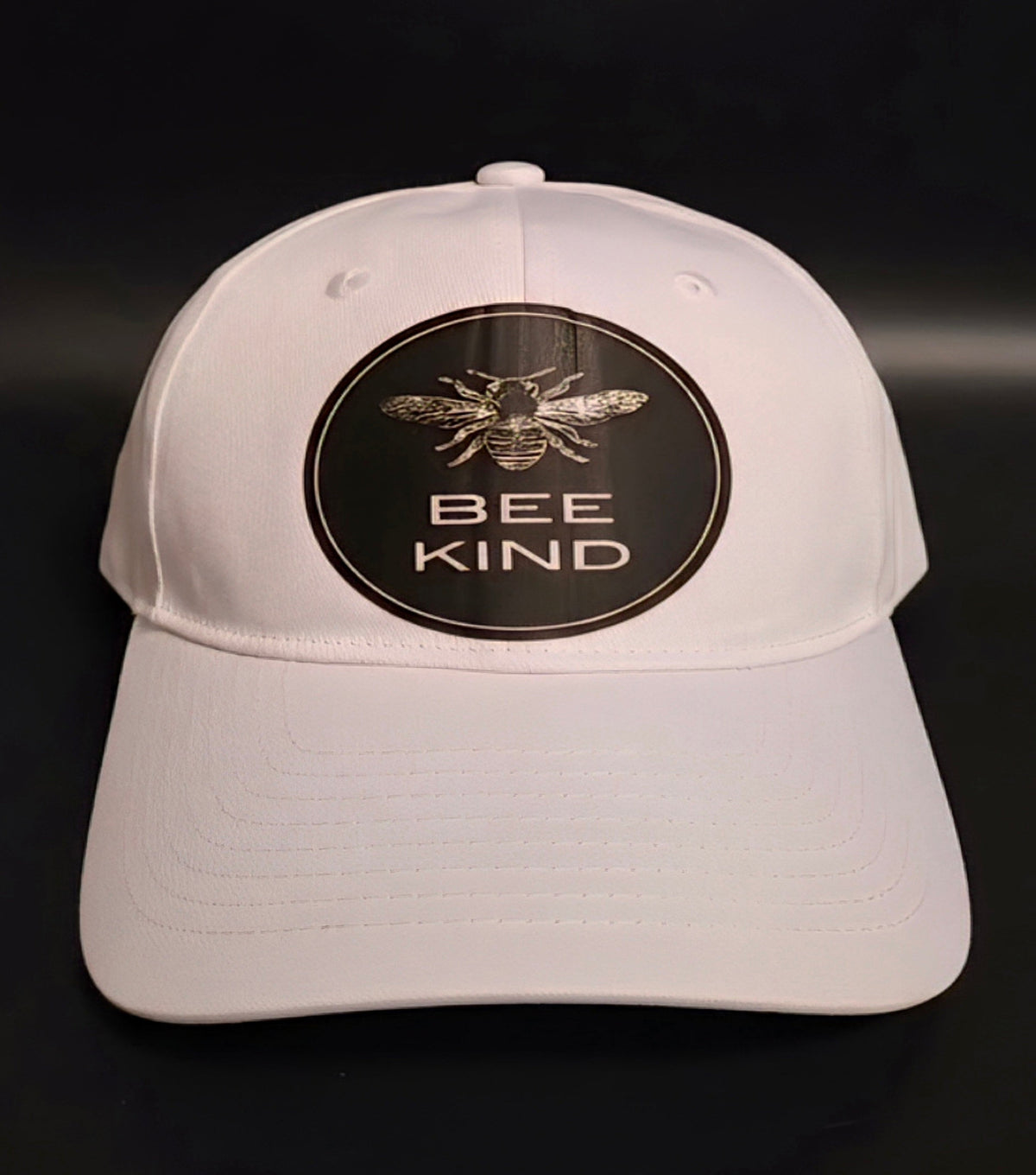 White cap with a honeybee graphic and BEE KIND message