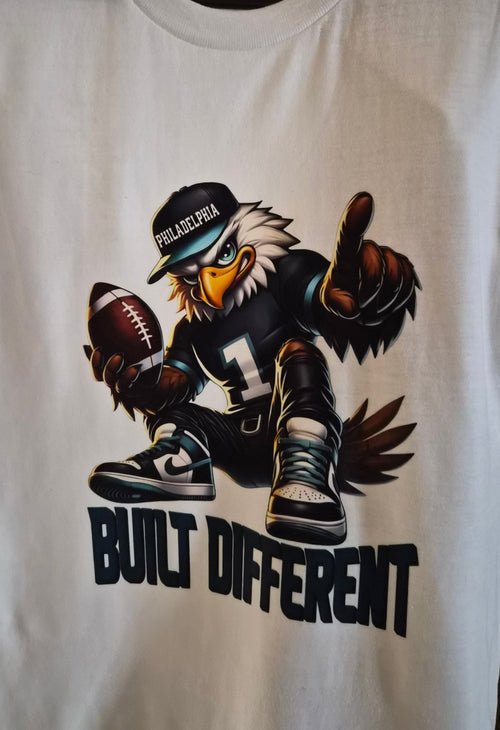 White graphic T-shirt with an eagle holding a football and Built Different text