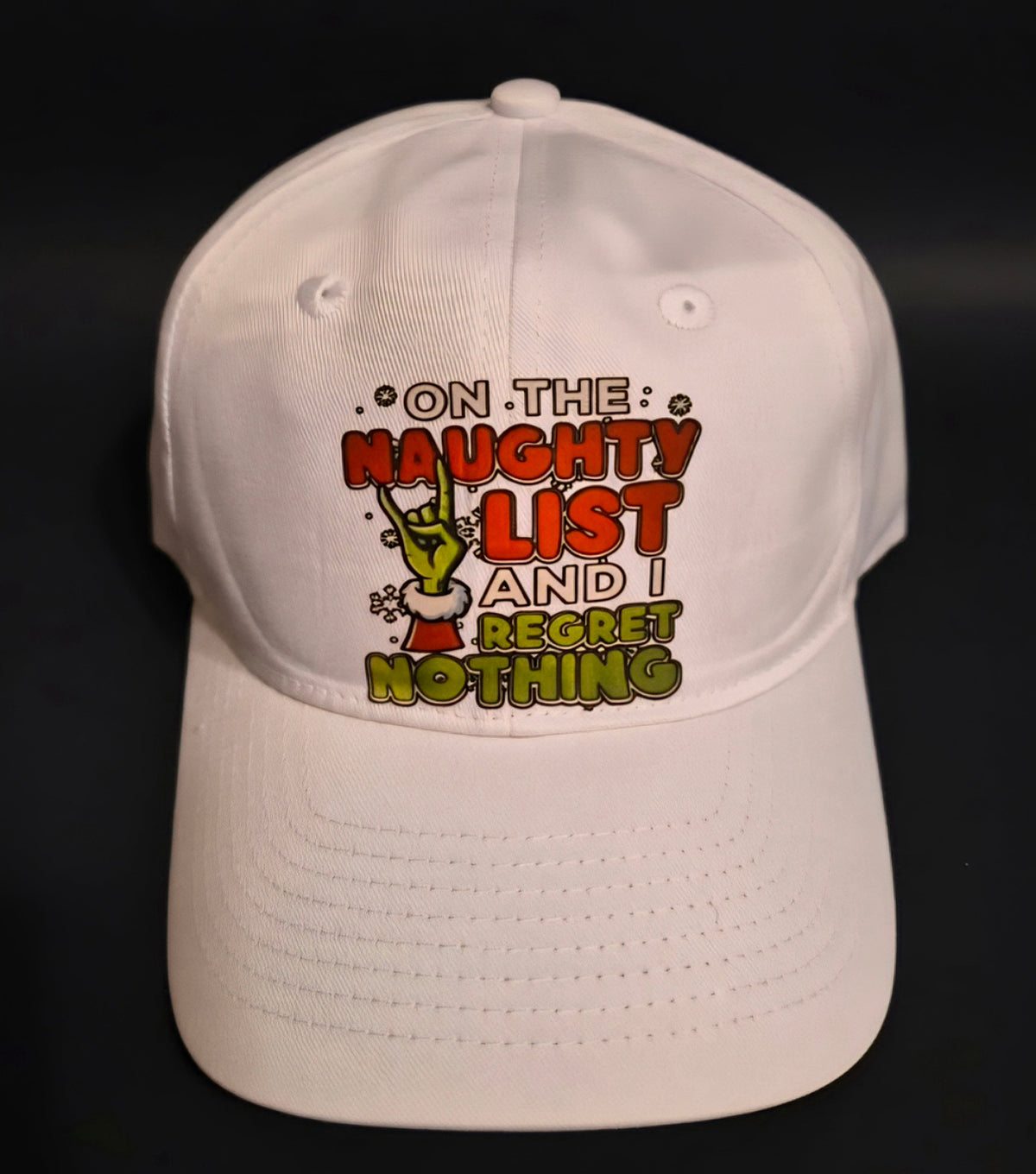 White holiday cap with a naughty list message and green character graphic