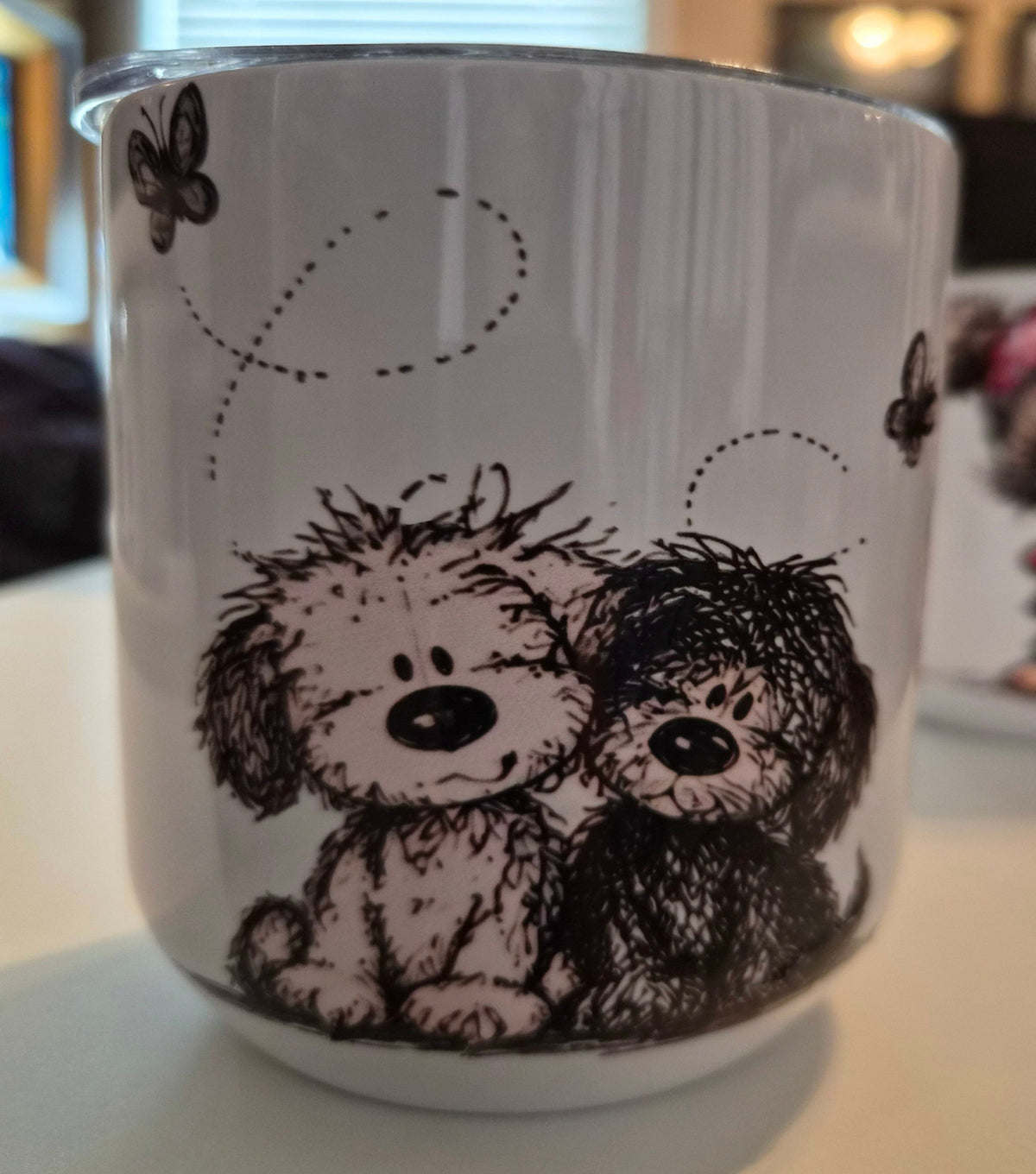 White Puppy Love tumbler featuring two shaggy black-and-white illustrated puppies with butterflies and dotted flight paths.