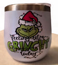 Green holiday character wearing a Santa hat with Feeling Extra Grinchy Today text and string lights on a white wine tumbler